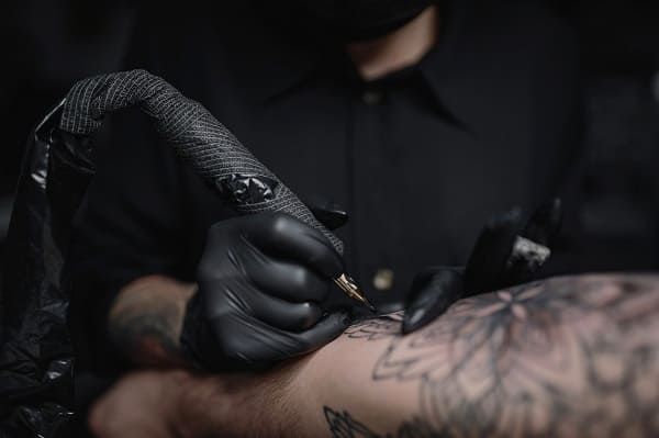 Professional tattoo artist creating intricate custom artwork in modern sterile studio environment